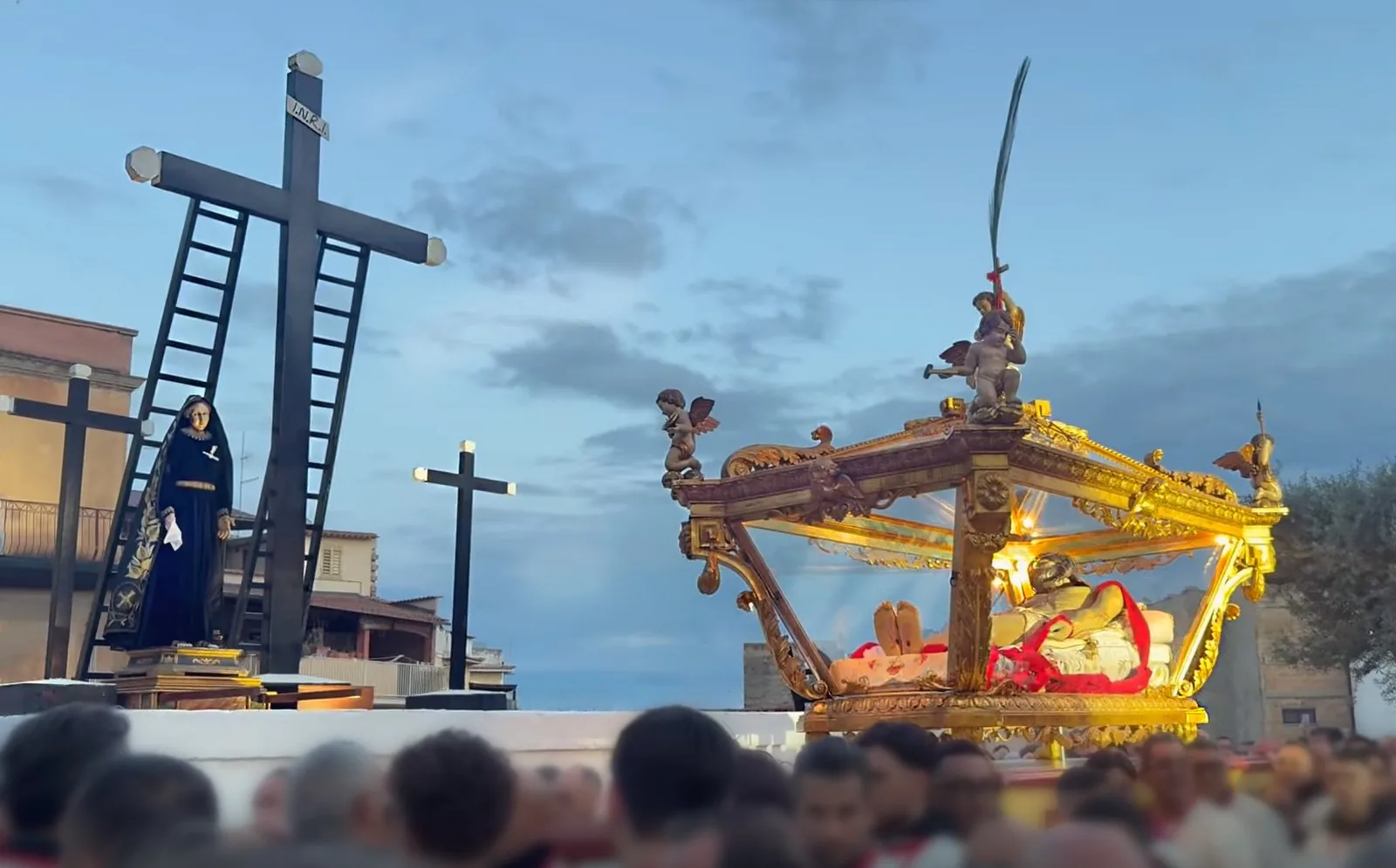 Processione religiosa serale con statue portate a spalla nel centro storico